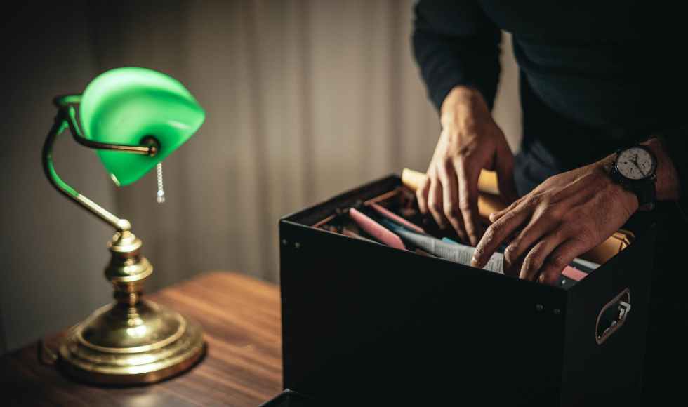 crop unrecognizable man looking through folder in home office